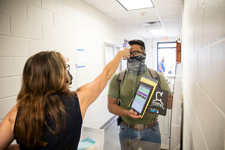 A student getting his temperature scanned.