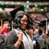 ACC Graduate at commencement in cap and gown smiling toward camera