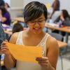 Student reading assignment paper in class while other students work at desks.  